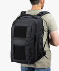 Back view of man wearing black Everyday Tactical Diaper Bag Backpack For Dads With Changing Mat Stroller Straps Built In Magnetic Wipes Pocket Cooler Pouch Thermal Pocket And Snack Space Black Everyday