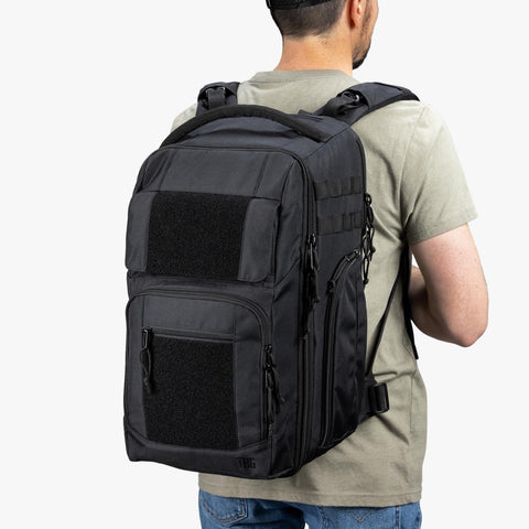 Back view of man wearing black Everyday Tactical Diaper Bag Backpack For Dads With Changing Mat Stroller Straps Built In Magnetic Wipes Pocket Cooler Pouch Thermal Pocket And Snack Space Black Everyday