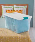 Super Tight Fit 64 Quart Clear Plastic Storage Bins 72 Pack With Snappy Hinged Lids on a bed containing a blue blanket.
