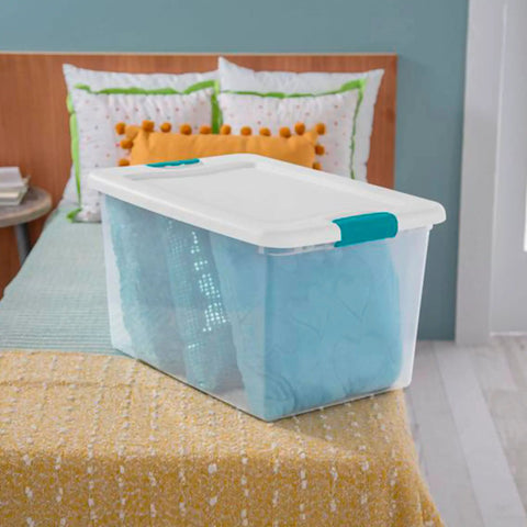 Super Tight Fit 64 Quart Clear Plastic Storage Bins 72 Pack With Snappy Hinged Lids on a bed containing a blue blanket.