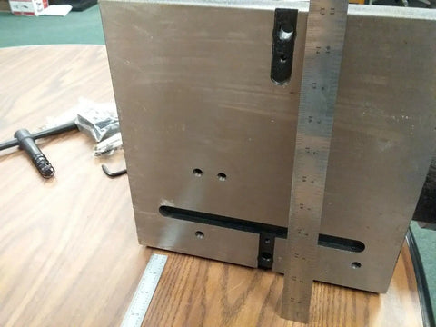 Close-up of Precision Tilting Rotary Table with Three Jaw Chuck and Six Inch Centering Adapter showing metal surface and ruler measurements.