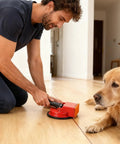 Man using Suction Cup Plank Grabber Floor Tool for Quick Easy Fixes Non Slip Heavy Duty Flooring Repair Kit near dog on laminate floor.