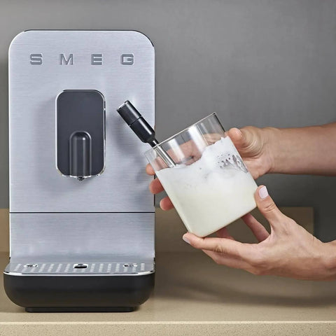 Person frothing milk next to Fully Automatic Coffee Machine With Steam For Home Use Black BCC12BLMUS Six Drink Options