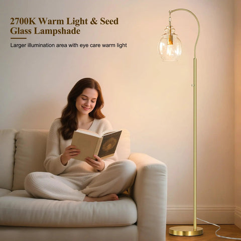 Woman reading next to gold modern floor lamp with globe glass shade, 68 inch tall mid century standing lamp for living room and bedroom.