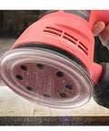 Image of a user operating a random orbital sander, showcasing the tool's hook loop base for 5 inch pads.
