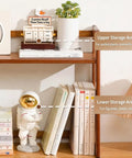 Wooden shelf with books, a small astronaut figurine, and a potted plant, showcasing upper and lower storage areas.