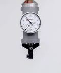 Front view of LLDSIMEX coaxial centering indicator; white dial gauge with black markings mounted on a tooling clamp.