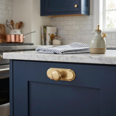 Champagne Bronze Cabinet Knobs With Orbit Rim Backplate Beaded Pull on navy cabinet against marble countertop