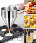 Smooth Pour 40 Oz Stainless Steel Pancake Batter Dispenser and Multi Nozzle Kitchen Funnel pouring batter into a muffin tin.