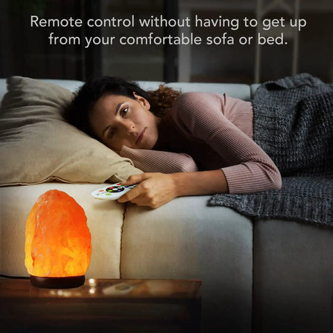 Woman using remote control for Himalayan Salt Lamp Night Light With Remote Control 5.5 Inch Pink Crystal Rock Light on bedside table.