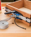 Band Clamp Accessory Kit With Plastic Boot And Rubber Retainer Strap For 1 X 15 Band Clamp And Older Clamps Helps Align Nylon Band When Rolling Up And Keeps Your Setup Tight And Ready To Go, showing clamp in use on wooden box.