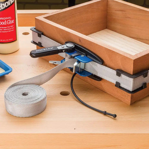 Band Clamp Accessory Kit With Plastic Boot And Rubber Retainer Strap For 1 X 15 Band Clamp And Older Clamps Helps Align Nylon Band When Rolling Up And Keeps Your Setup Tight And Ready To Go, showing clamp in use on wooden box.