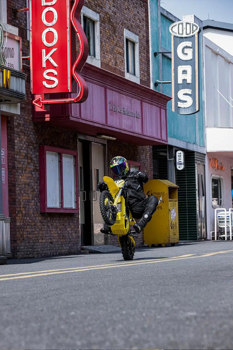 Rider performing a wheelie on a Heavy Duty Electric Dirt Bike Two Pack Crafted For Teens And Adults Packing 5500W Badass Motors With 276Nm Killer Torque Blasting To 55 Mph Plus A Dope Helmet Included For Off Road Adventures.