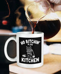 No Bitchin' In My Kitchen 11 Oz Ceramic White Mug With Comfortable Handle, coffee being poured, home or kitchen setting.