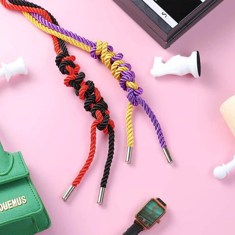 Colorful twisted ropes on pink surface with decorative items including green bag and watch.