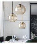 Nordic Industrial Glass Pendant Light Modern Single Lamp for Dining Bar Creative Decor,Artistic, three glass globes hanging above a dining table.