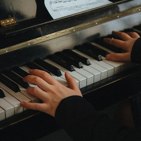 Hands playing piano keys with sheet music, showcasing Heavy Duty Long Folding Butt Hinges In Classic Antique Bronze Finish Pack Of Four Rock Solid Iron Hardware.