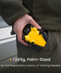 Person holding compact yellow Your Go To Ultra Light Drone With 4K Video, 8K Photo, Sub 249g Build, fitting in pocket.