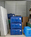 Ultra Large Moving Bags With Heavy Duty Zippers And Sturdy Carry Handles Waterproof Storage Bags For Moving Closet Organization And Camping 16 Pack Blue in storage unit with mattress and cardboard boxes.