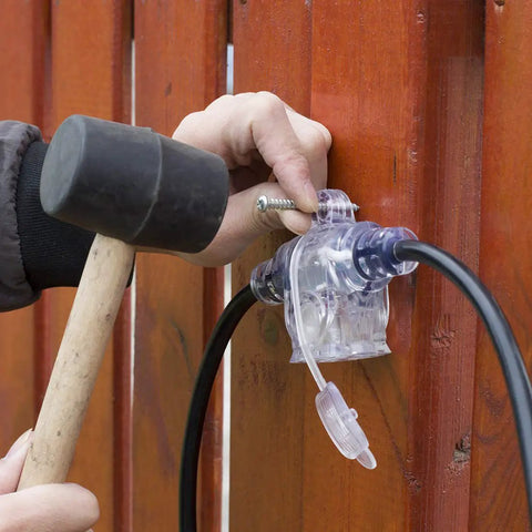 Person installing 50Ft Outdoor Power Extension Cord With Seven NEMA 5 15R Outlets 14 Gauge SJTW Cable on a wooden wall.