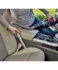 Person using Dustbuster 12V Car Handheld Vacuum With Extra Long Nozzle And Crevice Tool on car seats, red finish.