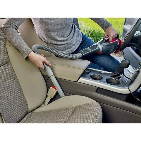 Person using Dustbuster 12V Car Handheld Vacuum With Extra Long Nozzle And Crevice Tool on car seats, red finish.