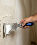 The Smooth Operator All In One Paint Brush And Roller Cleaning Tool With A Heavy Duty Paint Can Opener, using scraper on wall.