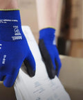 Person wearing HyFlex 11-618 Ultra Thin Nylon Safety Gloves For Automotive And Fabrication, Blue, handling components from a box.