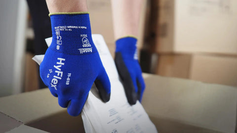 Person wearing HyFlex 11-618 Ultra Thin Nylon Safety Gloves For Automotive And Fabrication, Blue, handling components from a box.