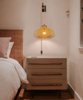 Rattan Hanging Light With Plug In Cord above nightstand, boho wicker basket lamp shade casting warm glow in cozy bedroom setting