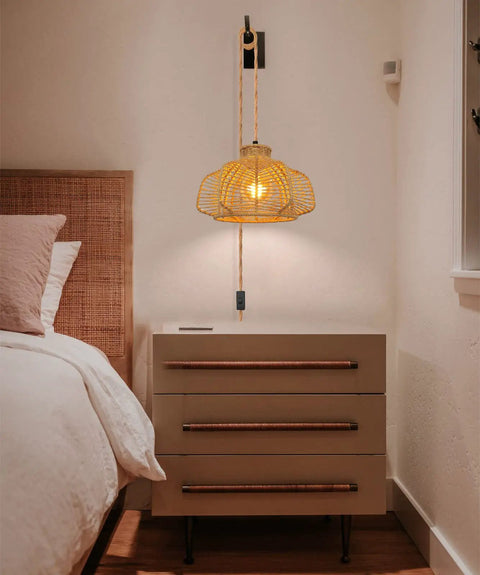 Rattan Hanging Light With Plug In Cord above nightstand, boho wicker basket lamp shade casting warm glow in cozy bedroom setting