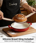 5 Quart Cast Iron Dutch Oven For Sourdough Baking With Domed Enamel Lid Round Bread Oven In Cherry Red Includes Silicone Bread Sling Perfect For Crusty Boules And Artisan Loaves, demonstrating silicone bread sling use with a baked loaf.