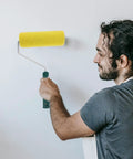 Person using a yellow Texture Pattern Paint Roller Sponge Brush For Walls Ceilings And Home Painting for wall painting.