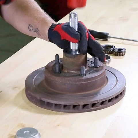 OEMTOOLS 27119 bearing race and seal driver set; gloved hand uses a steel driver on a rusted hub