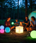 Family camping with Rechargeable 12 Inch LED Light Cube Stool With Remote Control Mood Lamp in various colors illuminating the night.