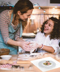 Two people baking in kitchen with Clear 6.4 Inch Square Acrylic Cookie Turntable With Non Slip Mat for cake and cupcake decorating.