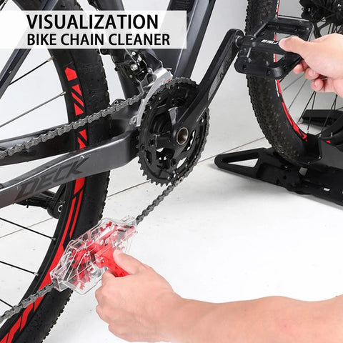 Using Ultimate Bike Chain Cleaning Kit With Deep 360 Degree Clean on bike with red accents, hand holding device on chain.