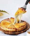 Close-up of small metal mini serving spatula with black handle lifting a slice of cheese pizza.