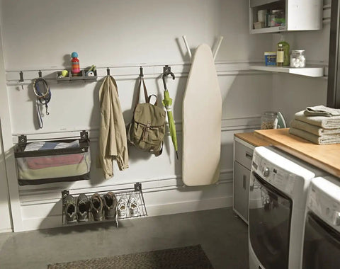 Garage wall with organized storage including basket and hooks on GearWall panel, ironing board, and bags for Six Pack Small Item Bins.