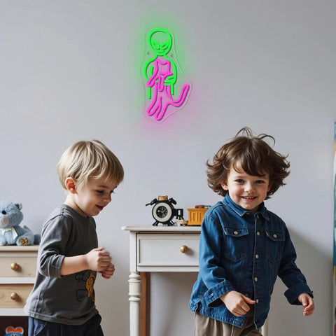 Two kids playing in a room with green and pink neon alien sign on wall above white dresser.