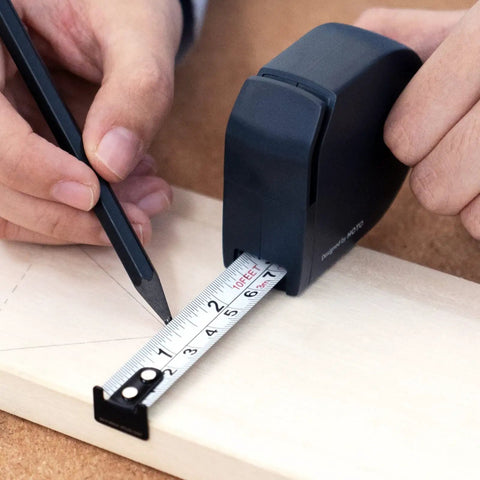Self Locking Tape Measure Pocket Size Retractable Dual Unit Feet Meters Gadget in use on wooden surface, navy color