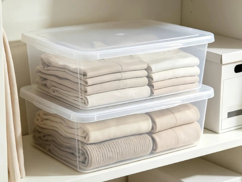 Heavy Duty Clear Plastic Storage Bins Are The Real Deal With Secure Snap Top Lid Stackable Under Bed Totes 28 Quart low profile bins organizing folded clothes on a shelf.