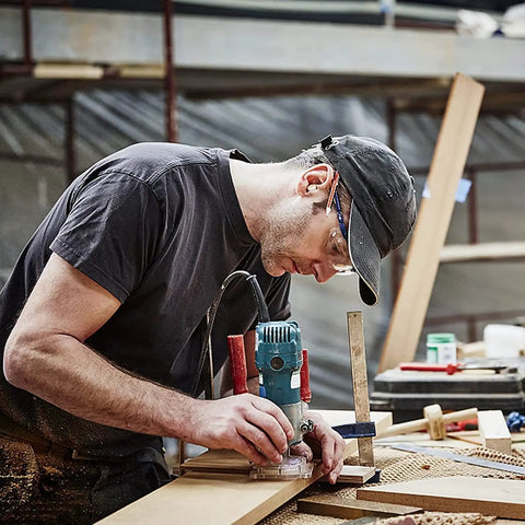 Carpenter using Pro Grade Top Bearing Flush Trim Router Bit Set Of 4 With 1/4 Inch Shank for edge trimming on wood surface.