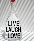 Glass bottle with 'Live Laugh Love' phrase in black vinyl letters, showcasing part of the 1260 Pcs Dope Vinyl Letter Stickers Set In 10 Sheets Black Self Adhesive Numbers Punctuation For Mailbox Signs Windows Doors Cars Trucks Home And Business Address Plaque One Inch Size Weatherproof Durable.