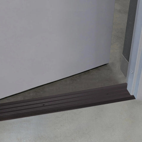 68395 Beefed-Up Aluminum Commercial Flat-Profile Threshold Bronze Finish For High-Traffic Doors Draft Protection Five Inches By One Quarter Inch By Thirty-Six Inches UL Fire Rated Durable Entryway Gap Sealer installed under a door.