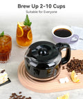 Black coffee pot with coffee beans on a wooden board, surrounded by beverages and pastries, emphasizing brewing 2-10 cups.