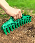 Hand using 12 Hole Digger Seed Spreader 7 Piece Seed Sowing Dispenser Set Tiny Handheld Seed Planter in soil, green plastic