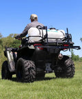 Person operating ATV with Beefy 15 Gallon ATV Broadcast Sprayer With 7 Ft Swath, 2.2 GPM Pump, 70 PSI Max, All Steel Boom on grass