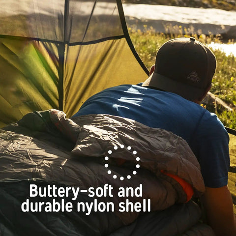Camper in tent using Cosmic Synthetic Fill 40 Degree Backpacking Sleeping Bag With Compression Straps Ultra Compact Regular Size.