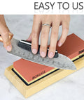 Person sharpening knife on Pro Knife Sharpening Stone Kit With 4 Sided Grit 400/1000/3000/8000 on bamboo base.